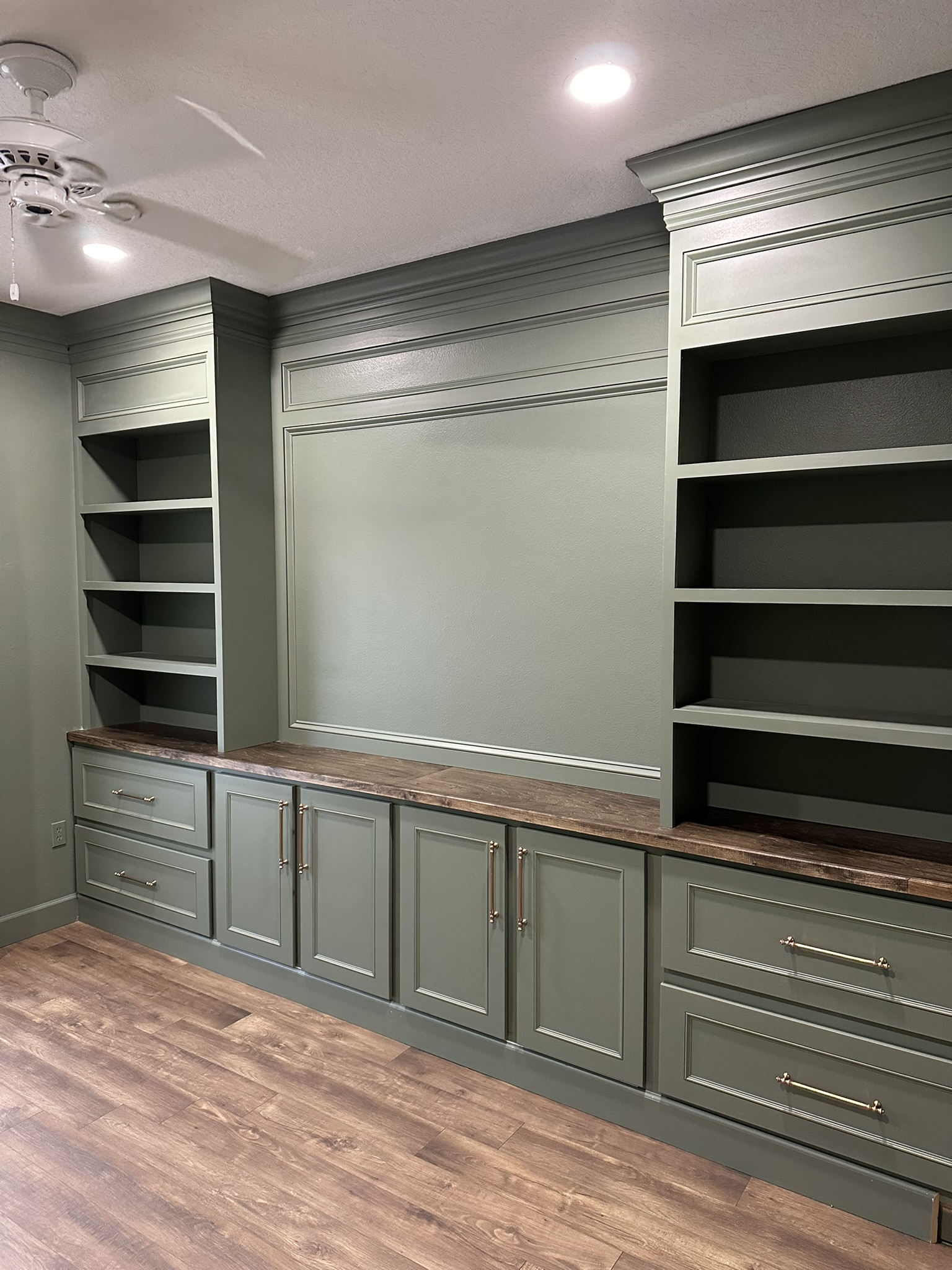 Green built-in wall unit with shelving and cabinets